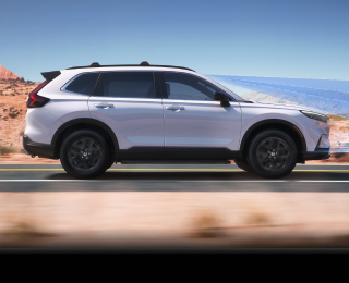 Sideview of white CR-V driving on desert highway. 