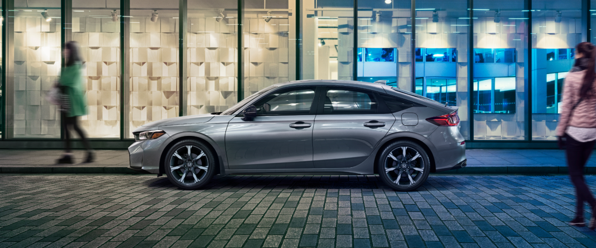 Side view of grey Hatchback parked outside an urban condo. 
