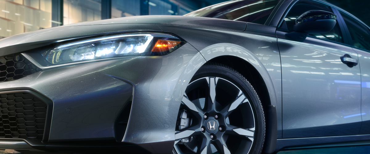 Close up of front view of a grey hatchback with lights on.