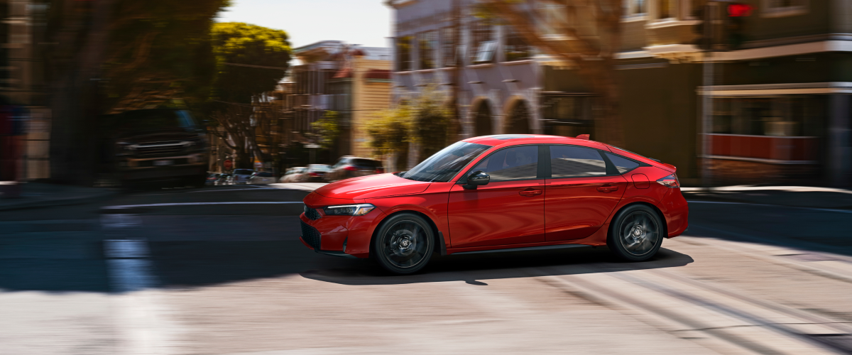 A red hatchback is parked outside a loft apartment.