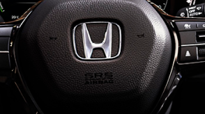 Closeup of steering wheel with Honda logo. 