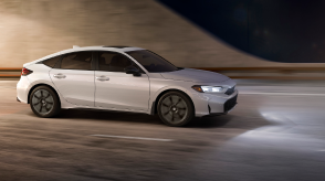 3/4 side front view of white Hatchback exiting a tunnel at night.