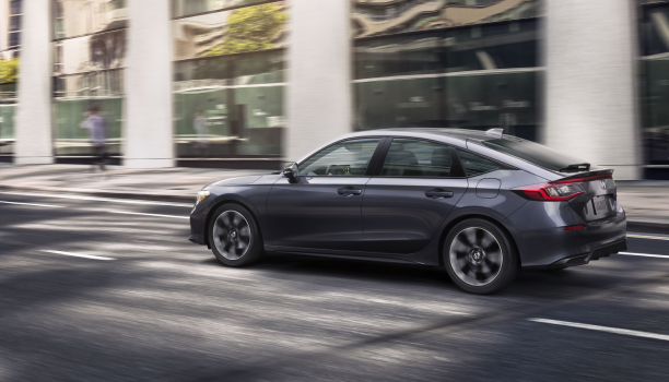 Side view of grey Hatchback driving on a city street. 