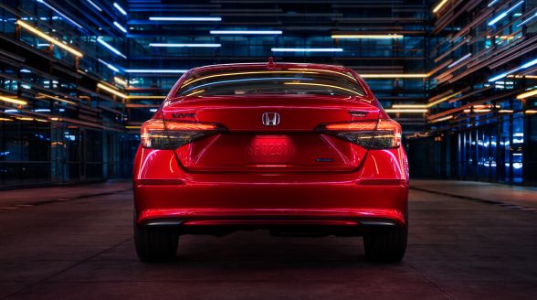 Rear view of a parked red Civic Sedan in a dark warehouse-like space.