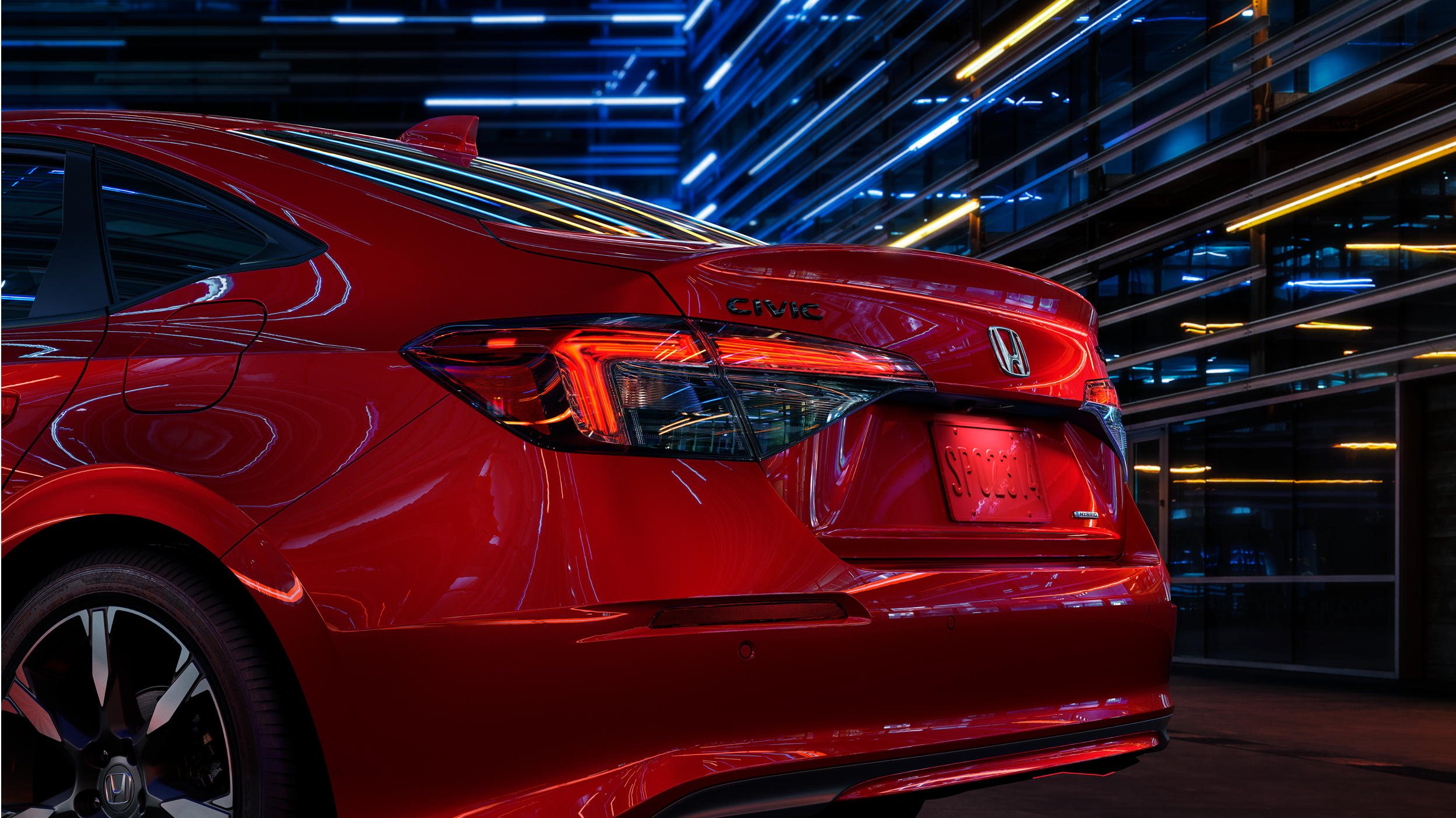 3/4 view closeup of taillight and trunk of a red Civic Sedan in a dark warehouse-like space.