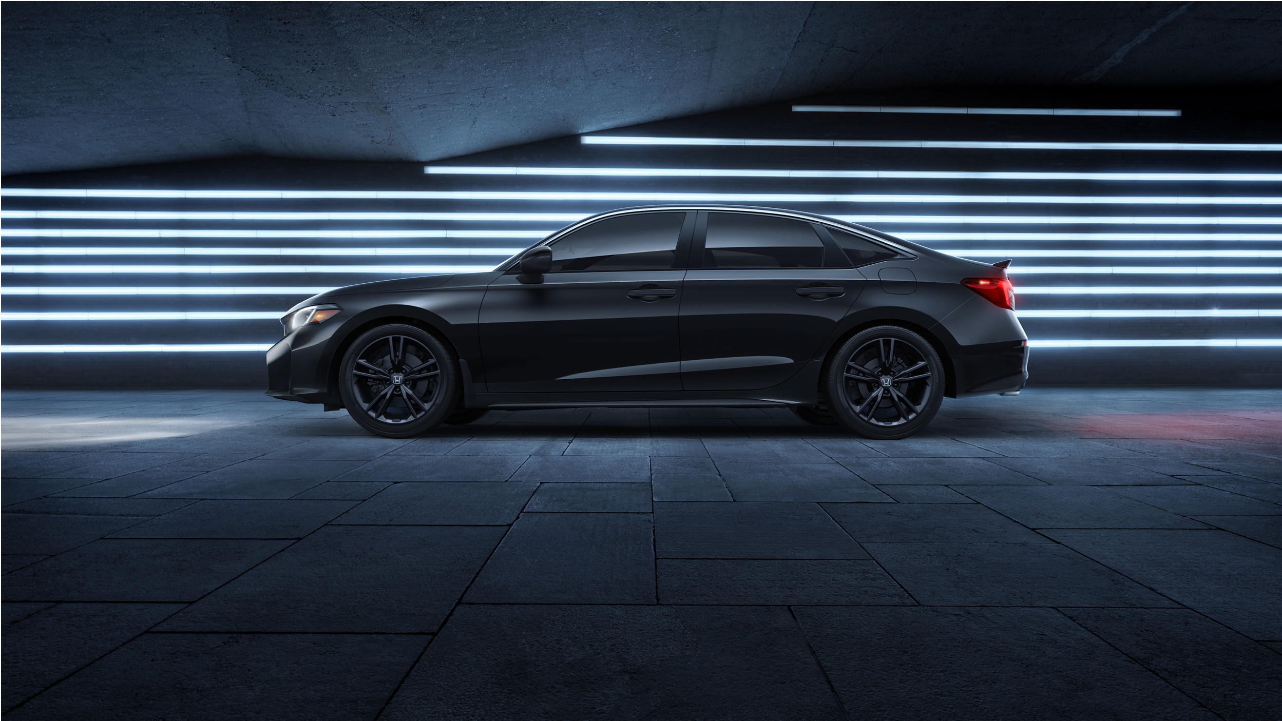 Sideview of black Civic Si parked in front of blue neon lights.