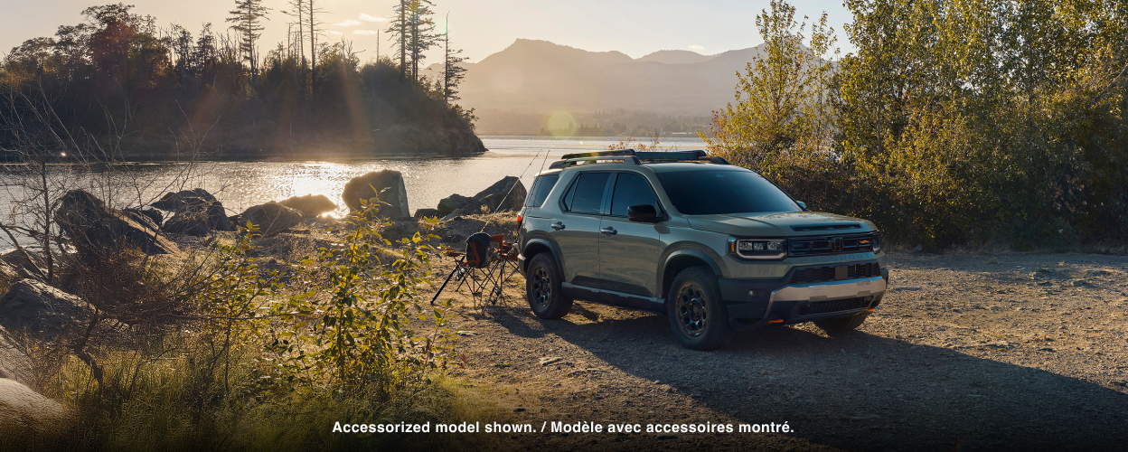 A grey Passport is parked in front of a lake. 