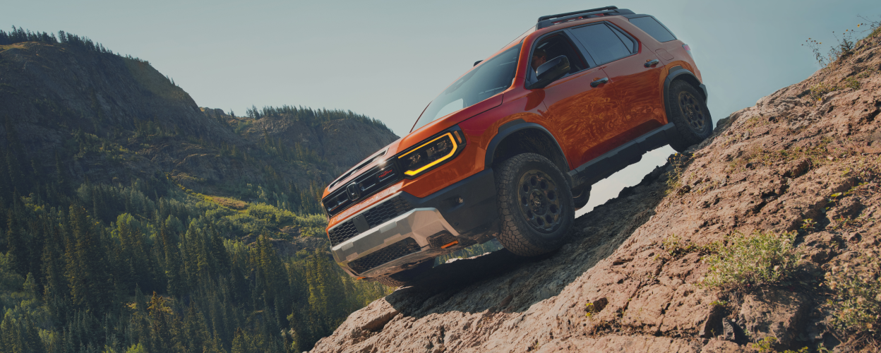 An orange Passport descends down a steep, rocky hill.