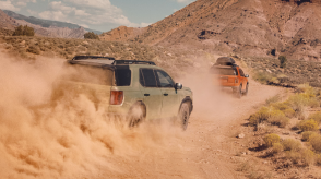 A green Passport drives through dusty desert terrain. 