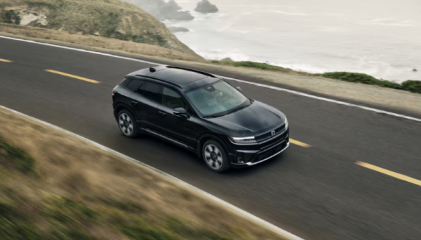A black Honda Prologue drives on an open, scenic highway. 