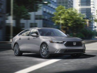 3/4 front view of grey Accord making a turn on a city street. 