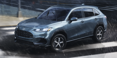 3/4 sideview of Nordic Forest Pearl colour HR-V driving in the rain in the city.